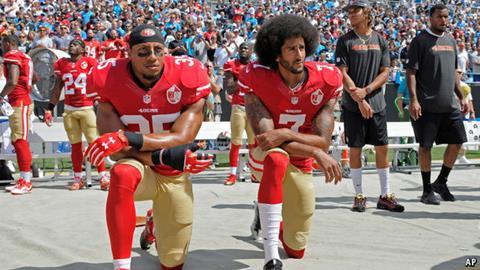Colin Kaepernick (right) kneeling for the national anthem