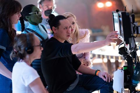 Centre L-R - Cynthia Erivo (as Elphaba), Director Jon M. Chu, and Ariana Grande (as Glinda) on the set of Wicked