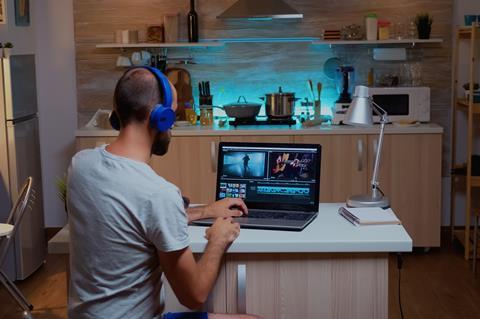 Creative filmmaker editing video footage in home using modern technology.